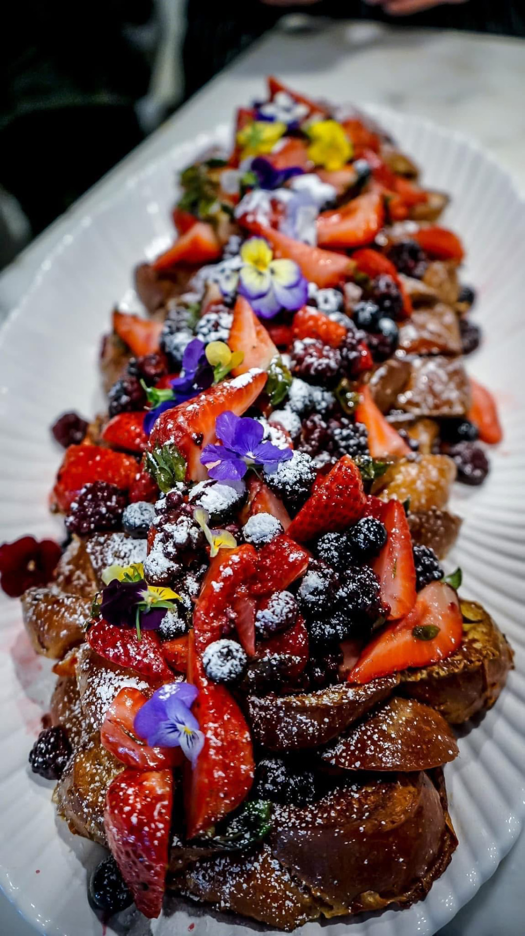 Berry-topped French toast dusted with sugar and edible flowers