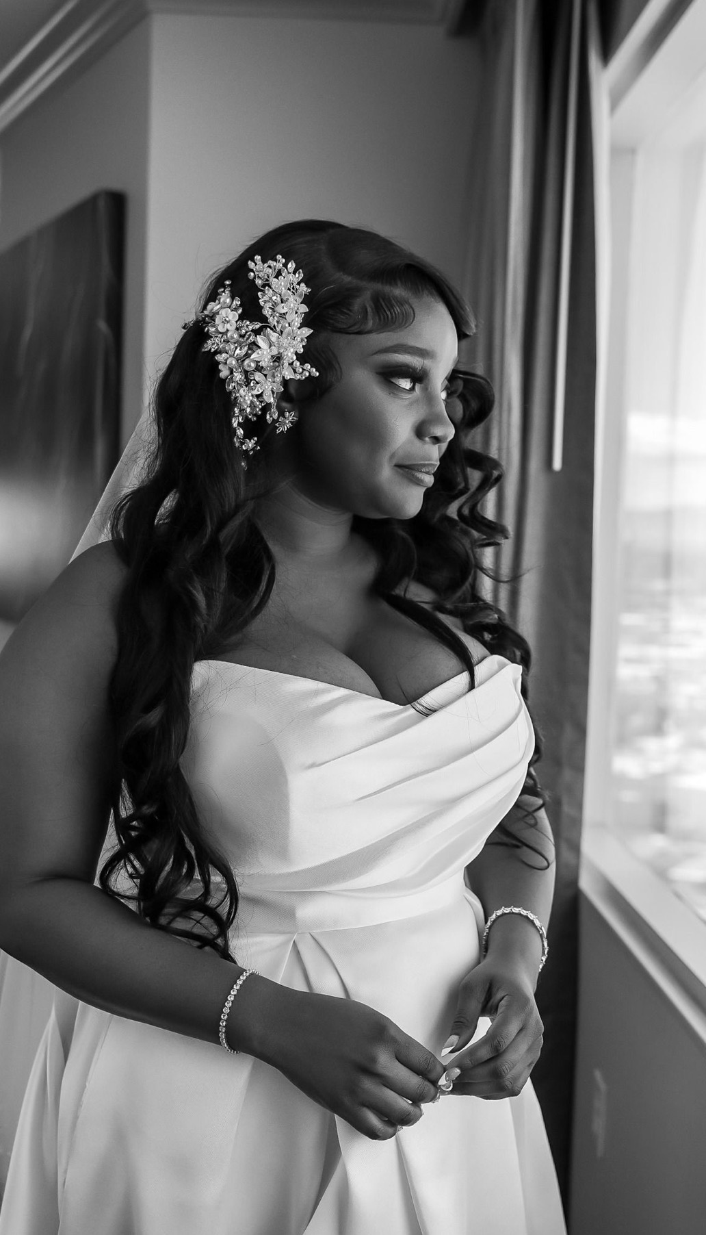Bride at the window in a satin gown with a pearl hairpiece
