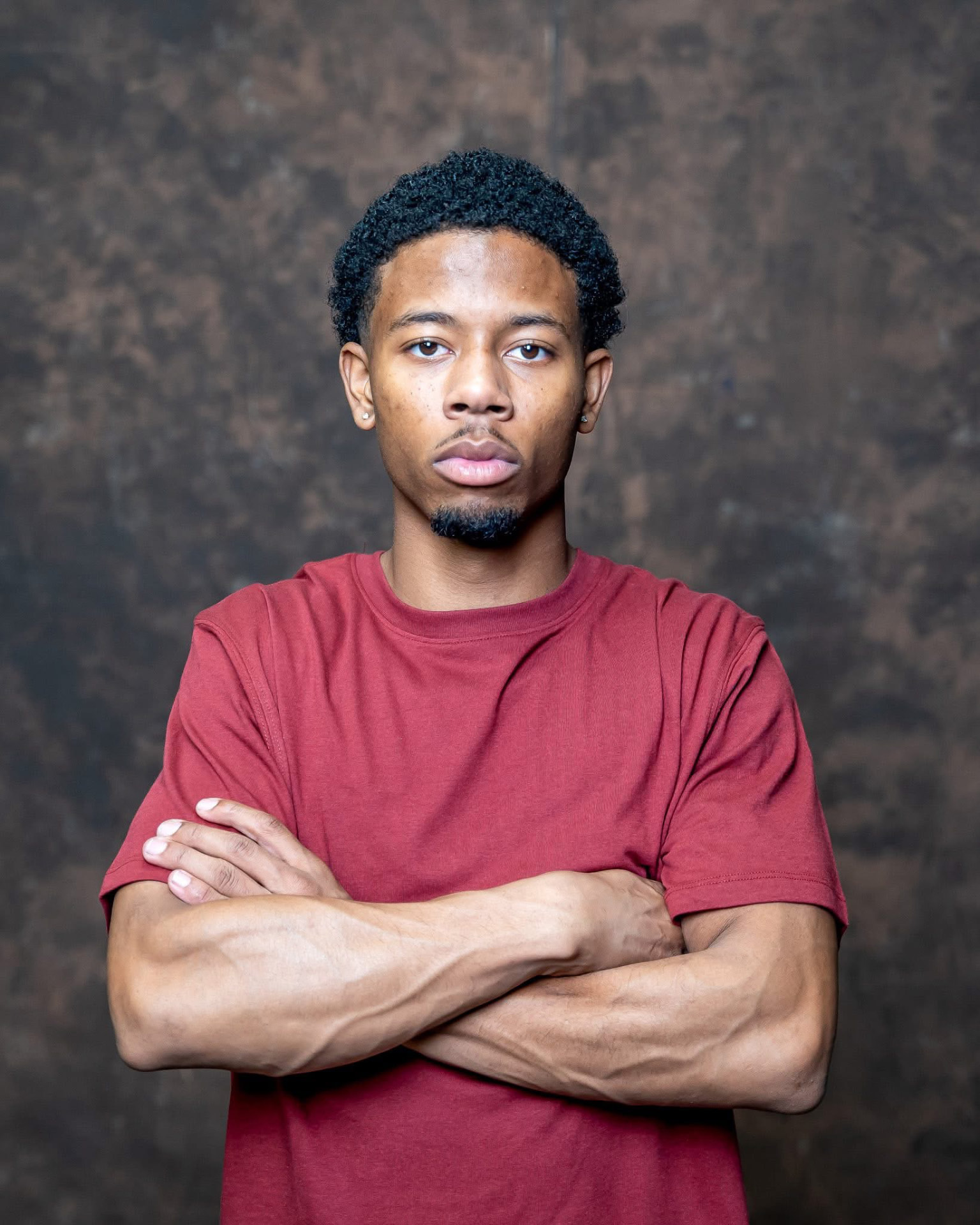 Studio portrait of a young man with arms crossed in a red tee