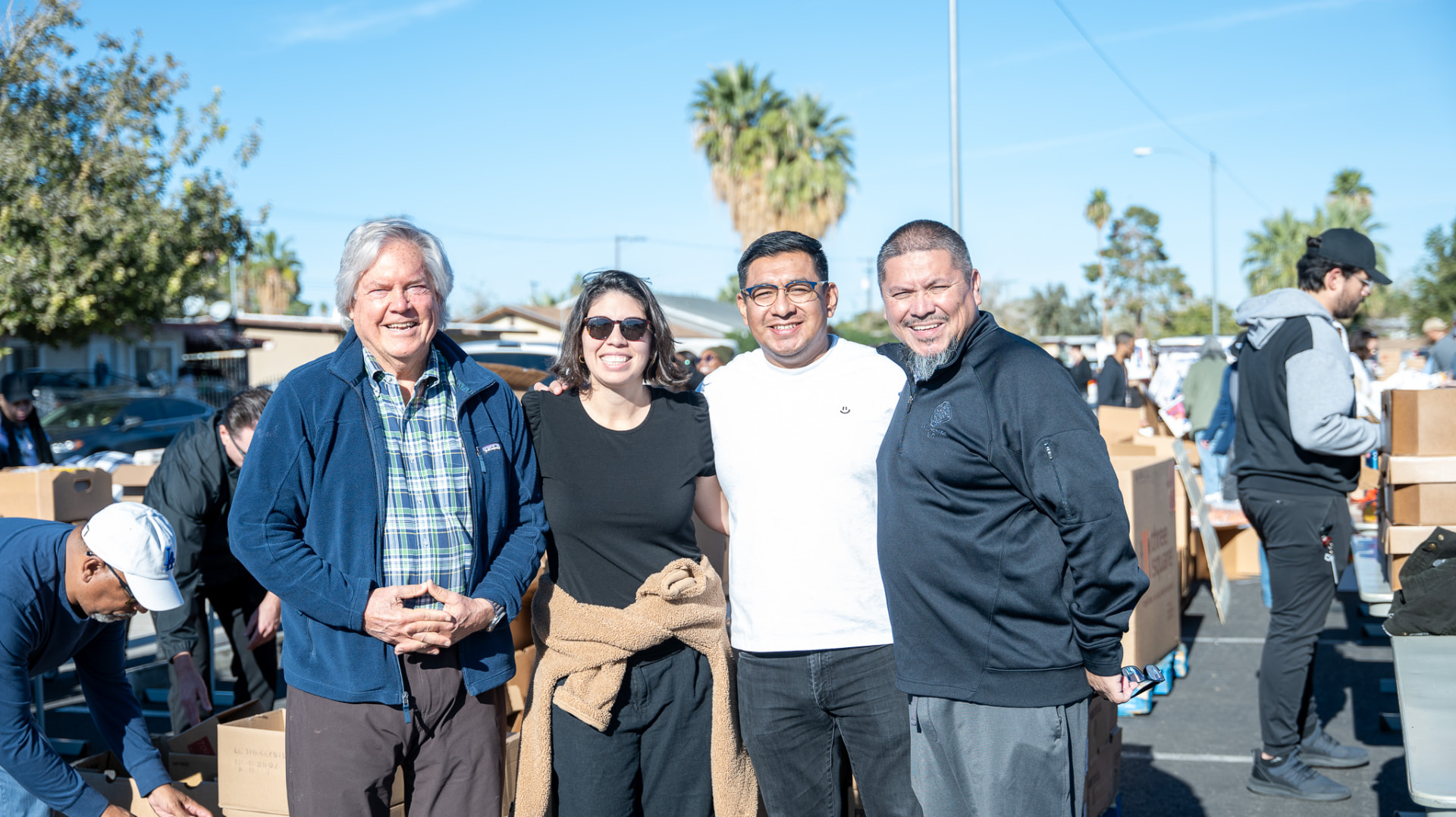 Volunteers smiling together at an outdoor community giveaway