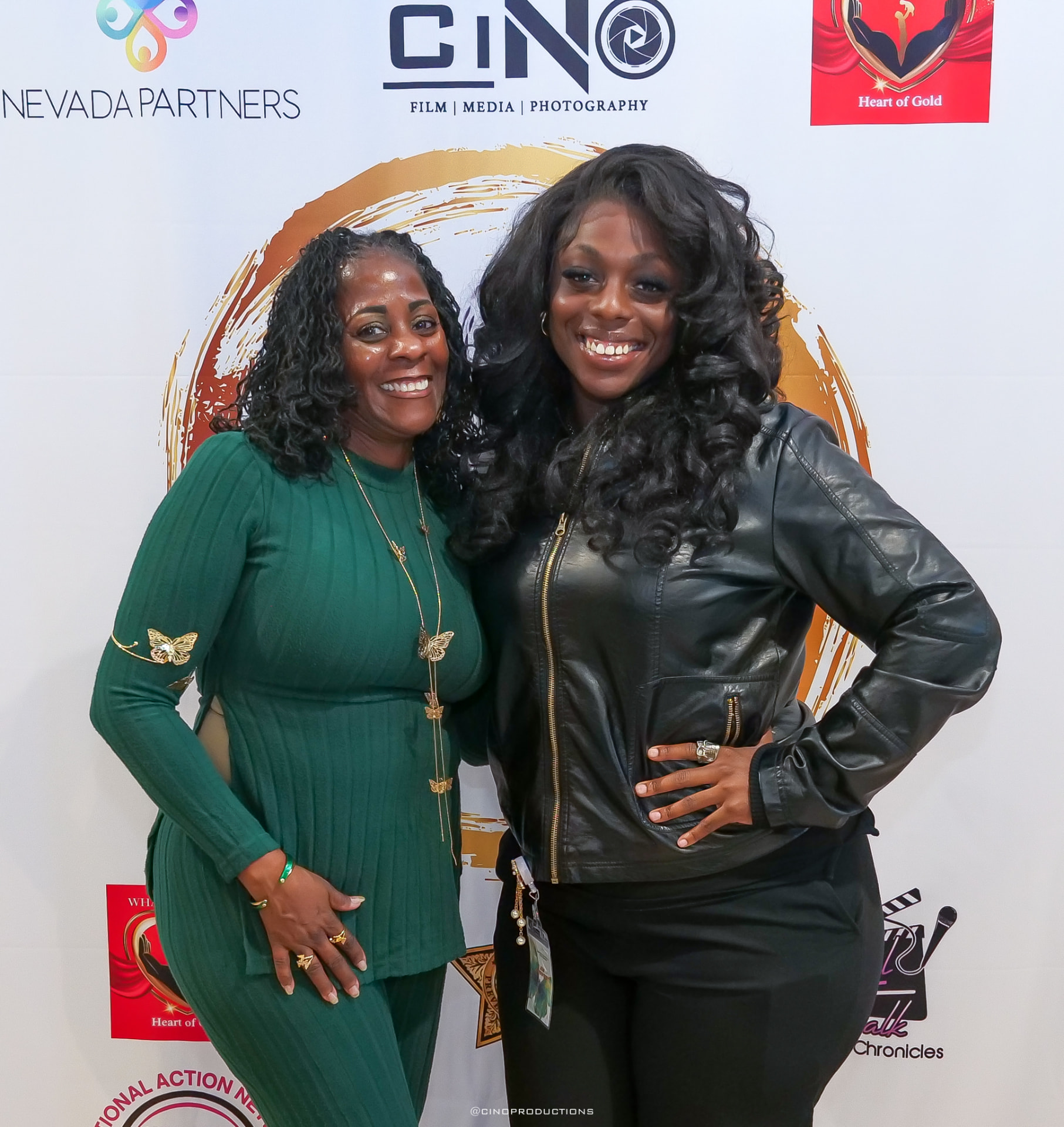 Two women posing on the CiNO Productions media wall