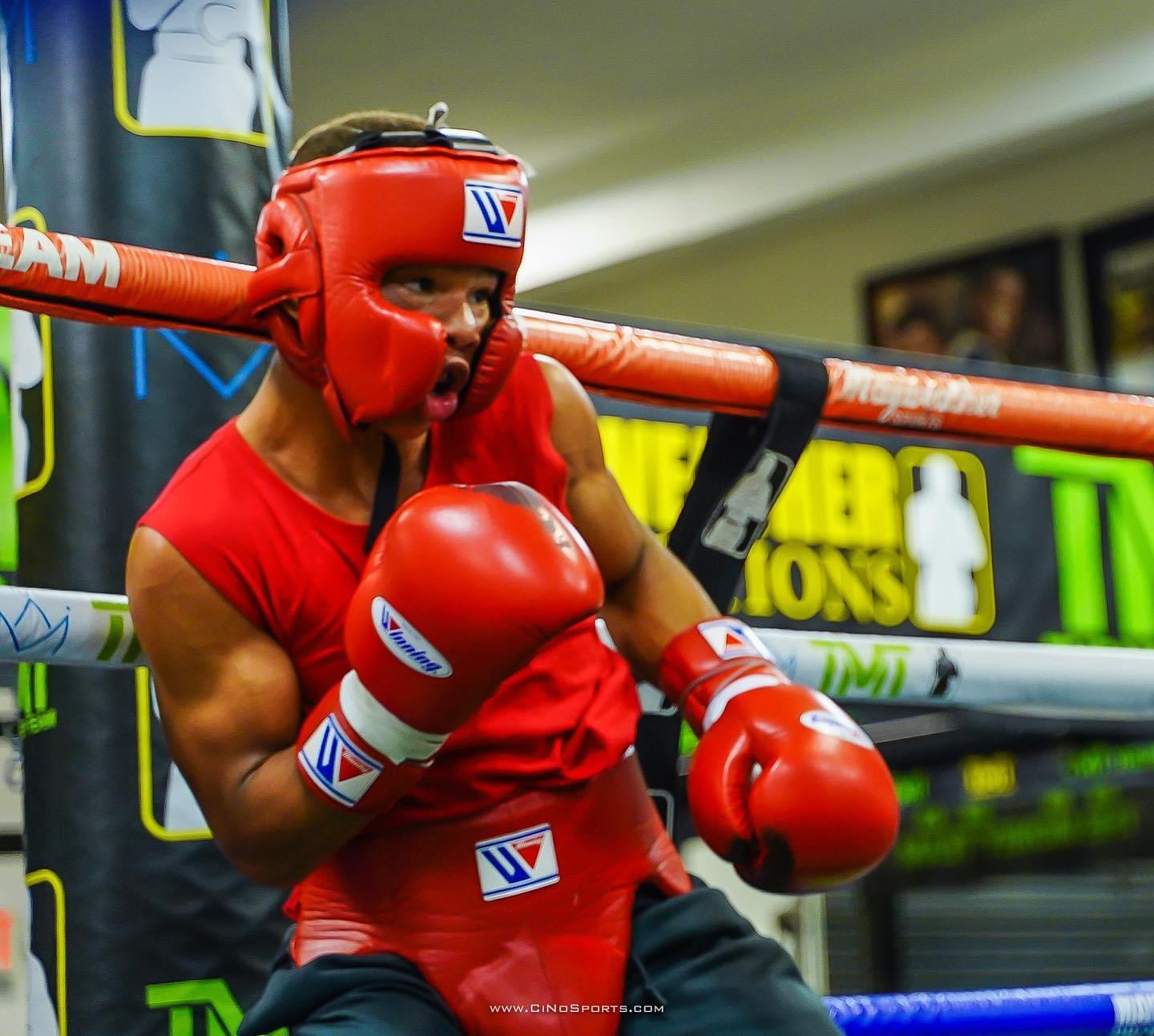 Young boxer in red headgear working in the ring