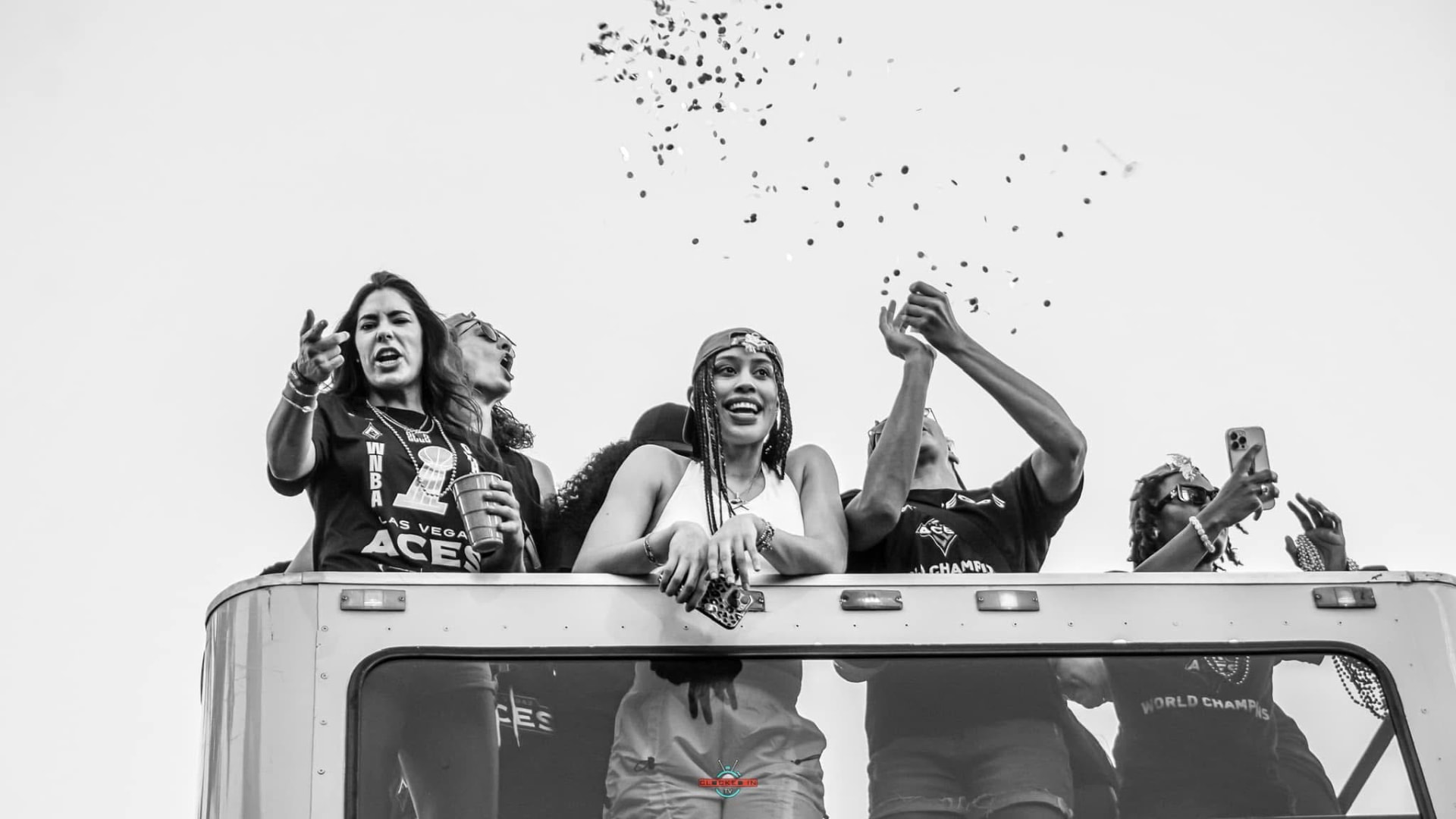 Championship team celebrating on a parade bus as confetti falls