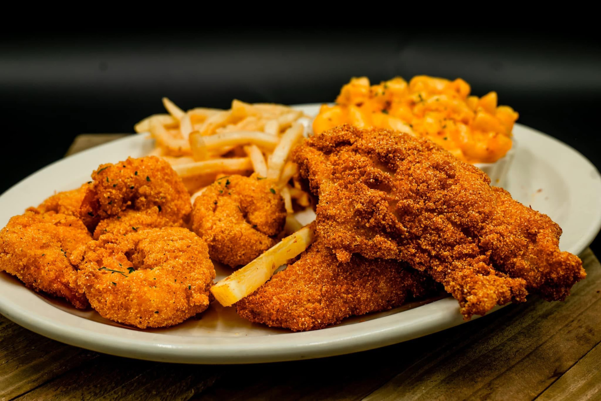 Fried catfish, shrimp, fries and mac and cheese plated on white