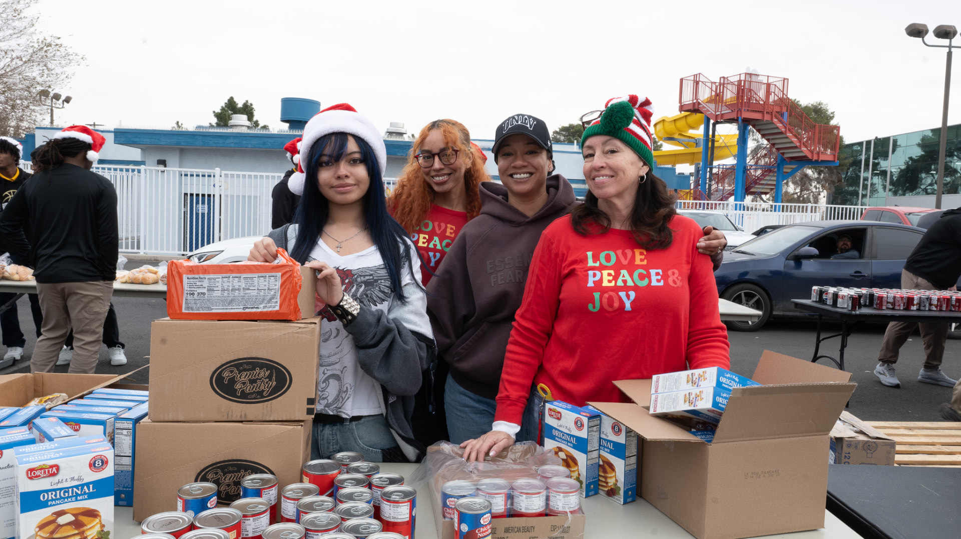 Volunteers behind tables of donated food at a winter giveaway