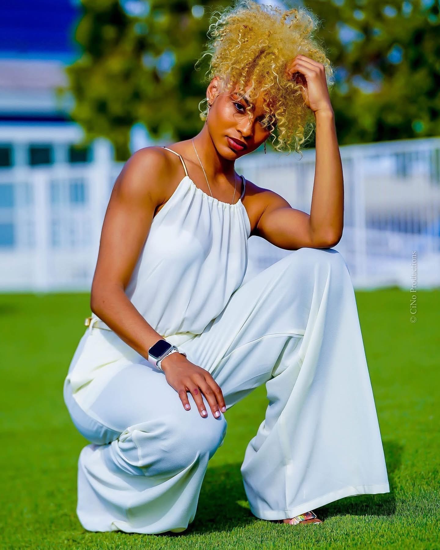 Portrait of a model in white kneeling on green lawn